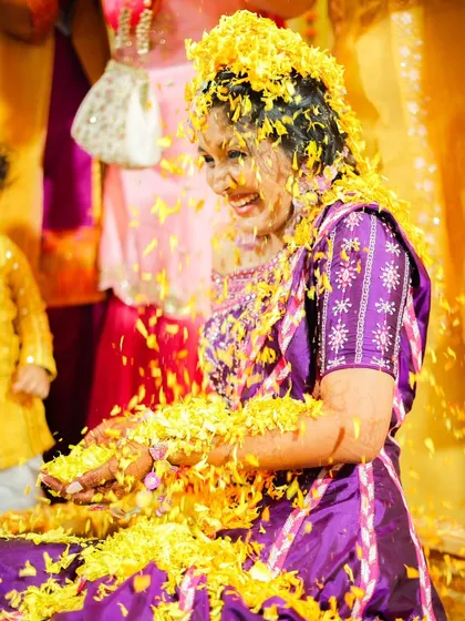 The bride's pure, uninhibited laughter as she's showered with flowers. These are the candid, joyful moments that make haldi so special.