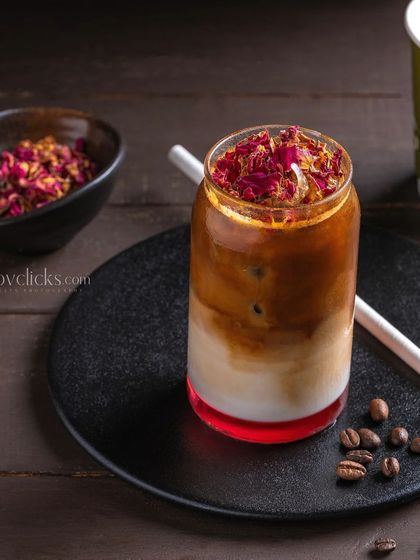 A rose-flavored iced latte, garnished with dried rose petals for an elegant and aromatic touch.