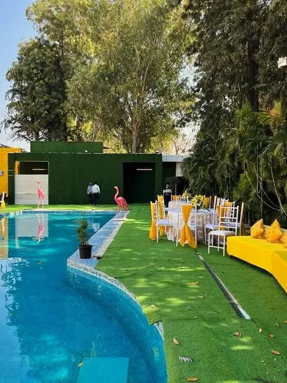 A poolside Haldi setup with bright yellow lounge seating. The pink flamingo props add a quirky and fun element to the overall decor.