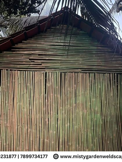 A full view of the completed bamboo house, showcasing its traditional gabled roof with Mangalore tiles and natural bamboo walls.