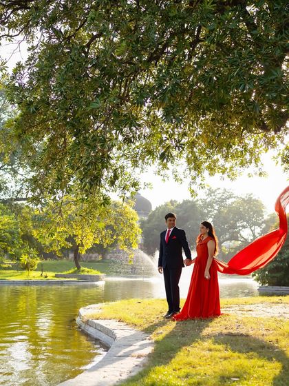 The warm, sunny glow of golden hour perfectly complements this orange-red crepe trail gown. It's a beautiful choice for a romantic walk in the park.