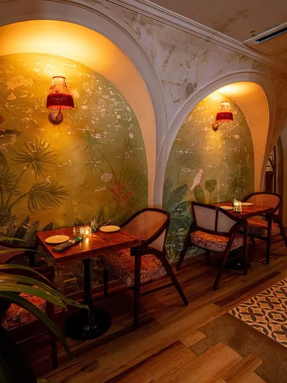 A closer look at the slender corridor in Los Cavos, where skewed arches frame each seating arrangement. The distressed finish on the walls and the warm, decorative lighting enhance the intimate and historic feel of the space.