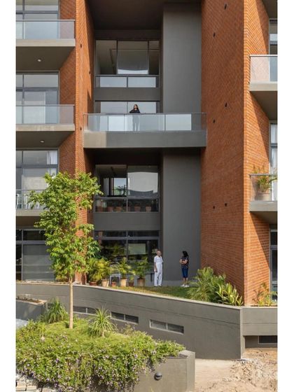 The building's facade features recessed balconies and large windows, providing residents with private outdoor space and ample natural light while maintaining a cohesive architectural language.