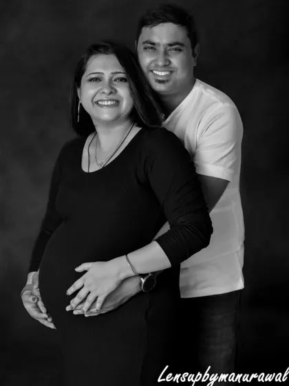 The pure happiness of starting a family together. This classic black and white studio portrait captures the joyful smiles and close embrace of an expecting couple, a perfect memory of this special time.