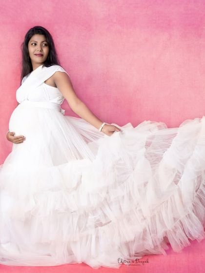 A classic white gown against a soft pink backdrop. The flowing train adds a touch of romance and elegance to the shot.