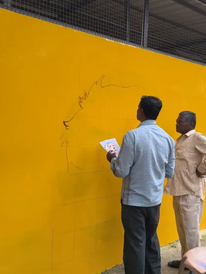 An artist consults his reference photo as he begins to sketch the large mural. This wall is being transformed into a symbol of the love that defines VOSD.