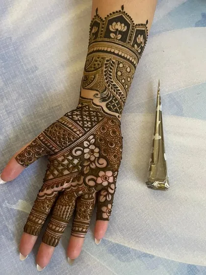 Here you can see one of my intricate wrist and hand designs next to the very cone I used to create it. My cones have a fine tip for precision, allowing for detailed work like the florals and geometric patterns shown here.
