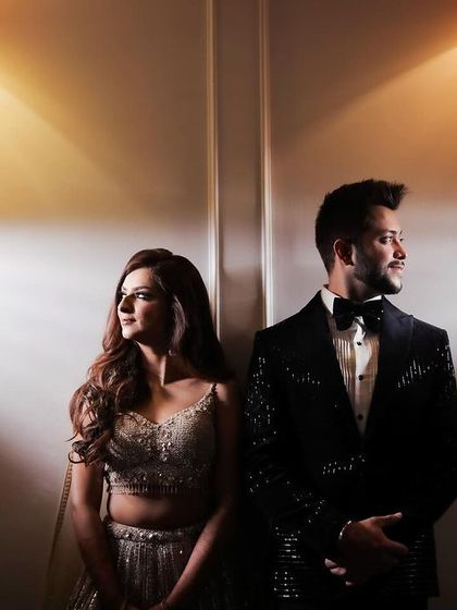 A stylish portrait of a couple for their engagement, using dramatic spotlighting against a plain wall to create a modern and clean look.