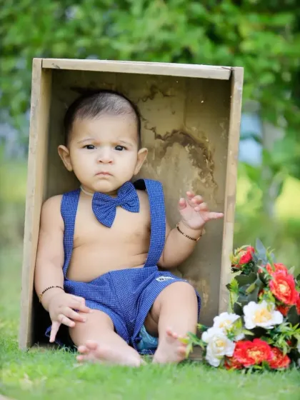 A simple and sweet outdoor portrait of a baby boy in a wooden box, surrounded by grass and flowers.