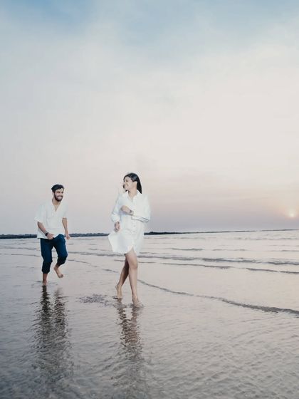 A beautiful action shot of the couple running along the shoreline at sunset, creating a dynamic and romantic silhouette.