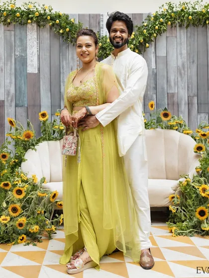 A full-length portrait of the couple at their Mehendi ceremony, posing against a lovely sunflower backdrop.