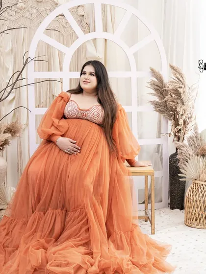 A beautiful portrait from another of our boho sets, featuring a white arched window and earthy orange tones. The mom-to-be looks stunning in a burnt orange gown.