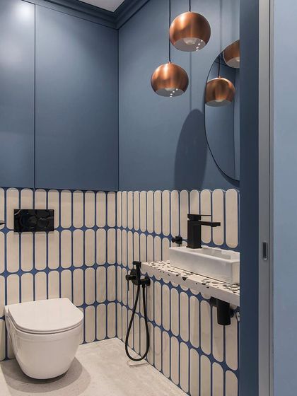 Colors and patterns are crucial for any space. This compact powder room uses bold blue walls, uniquely patterned tiles, and copper pendant lights to make a big design statement.