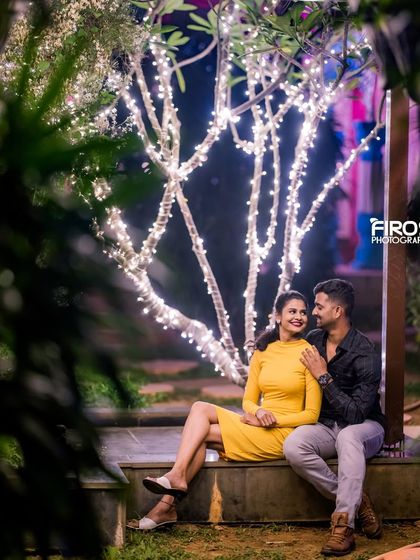 A quiet moment shared under a tree wrapped in fairy lights, perfect for a casual and romantic night-time shot.