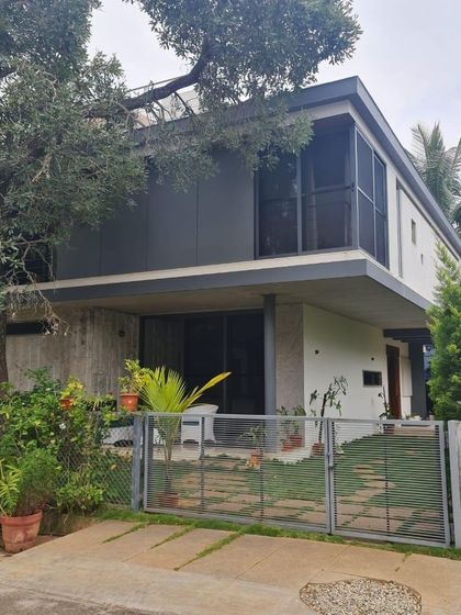 "Casa Magnifera" is a study in modern tropical architecture. The design features a simple cubic form with a cantilevered upper level, using a palette of grey cement board and exposed concrete to blend with the lush green surroundings.
