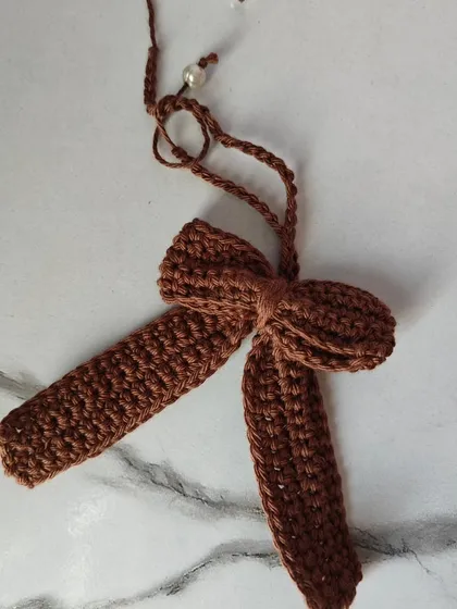 A close-up of the earthy brown crochet bow. The color is so versatile, and the simple design makes it a timeless piece.