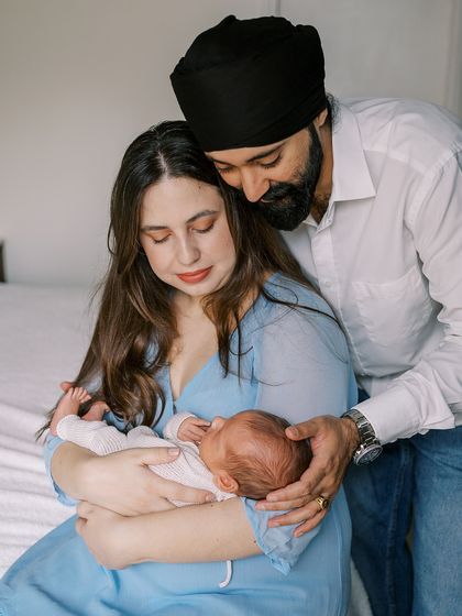 A quiet, intimate portrait of a family with their newborn. The focus is on their gentle touch and loving expressions.