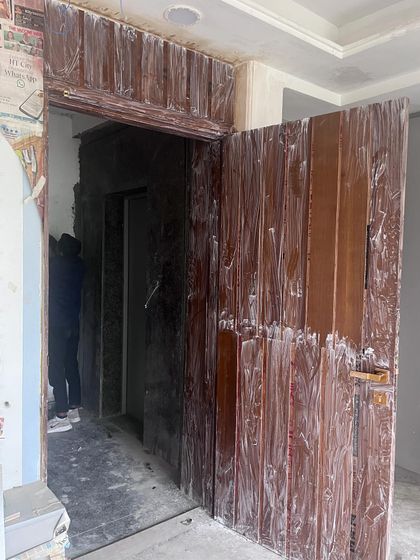 This photo shows the main door and entrance area during construction. The wooden panels are being installed, giving a hint of the warm and textured design to come.