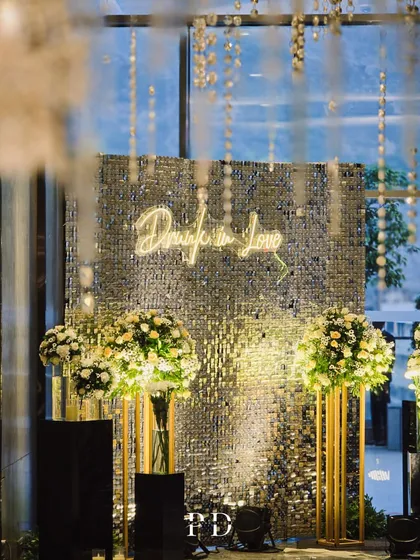 The silver sequin photo booth, framed by hanging crystals and lush floral arrangements, creates a perfect spot for guests to capture memories.