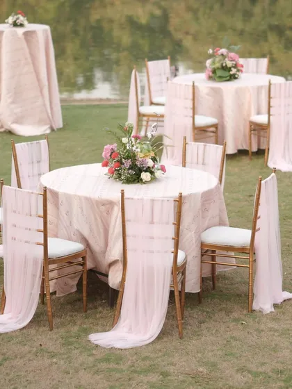 Elegant guest seating at the 'Mantram' wedding. The tables were dressed in soft pink linens with flowing chair drapes, creating a romantic and dreamy dining experience by the water.