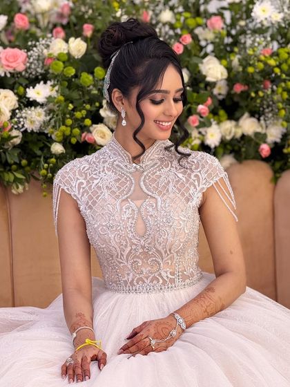 A portrait of the bride in her white reception gown, showcasing her sophisticated updo and the delicate details of her dress.