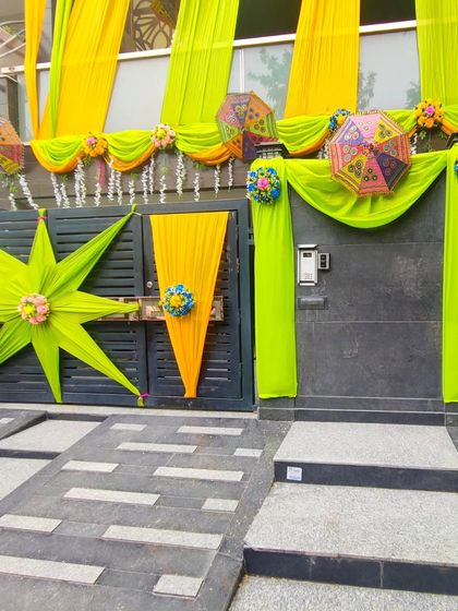 A unique gate decoration using lime green and yellow drapes in star shapes and cone styles for a modern, artistic touch.