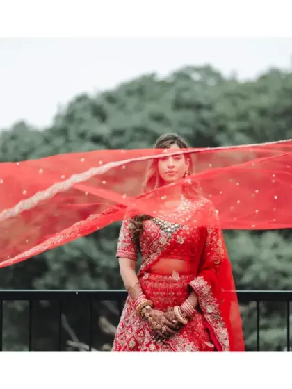 The bride's red veil flows dramatically in the wind, creating a powerful and artistic bridal portrait. This shot captures the movement and emotion of the day against the misty Mahabaleshwar backdrop.