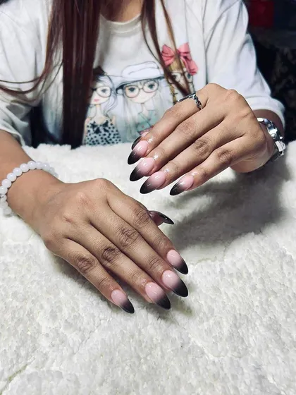 A black ombre or 'smoke' effect on the tips of almond-shaped nails. This is a subtle yet edgy look that is very popular with clients.