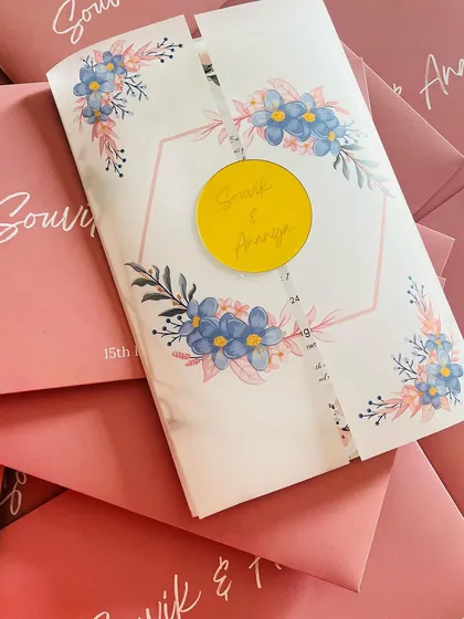 This is a great example of a modern and elegant wedding invitation. It features a delicate watercolor floral design on a translucent vellum wrap, sealed with a custom gold acrylic monogram of the couple's names.