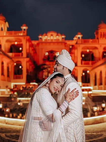 A tender embrace against the beautifully lit facade of Rajasthali Jaipur. We use the ambient light of your venue to create warm, romantic, and unforgettable night portraits.