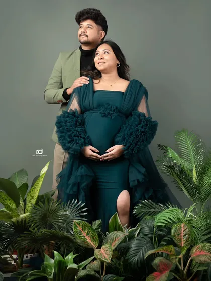 A stylish couple's portrait with a nature-inspired theme. The greenery complements the deep green gown and the couple's modern outfits perfectly.