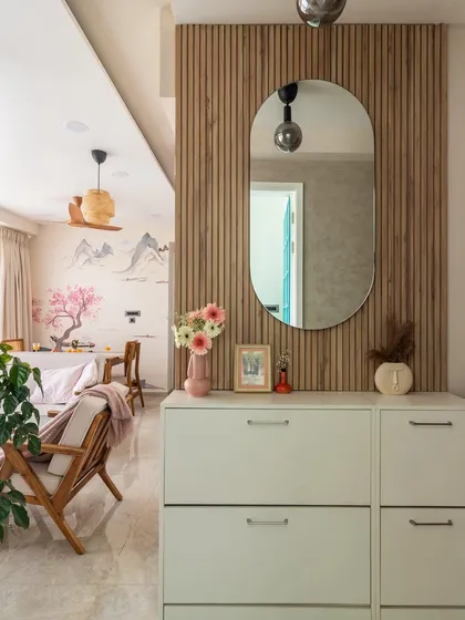 The foyer in our Japandi-style home features a louvered panel and an elegant oval mirror, creating a sense of grandeur and a warm welcome.