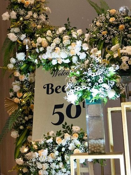 A different perspective of the 50th birthday welcome area. The lush floral arrangements and gold accents created an opulent and inviting atmosphere for the grand celebration.