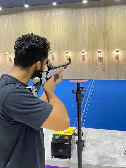 A shooter takes aim with an air rifle in our well-lit, wood-paneled range, showing the clean and professional environment we provide.