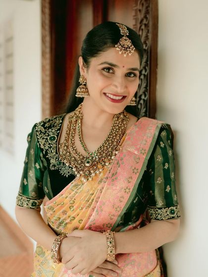 A smiling bride, happy and confident in her chosen attire. The traditional jewelry and the vibrant silk saree come together to create a perfect bridal look.