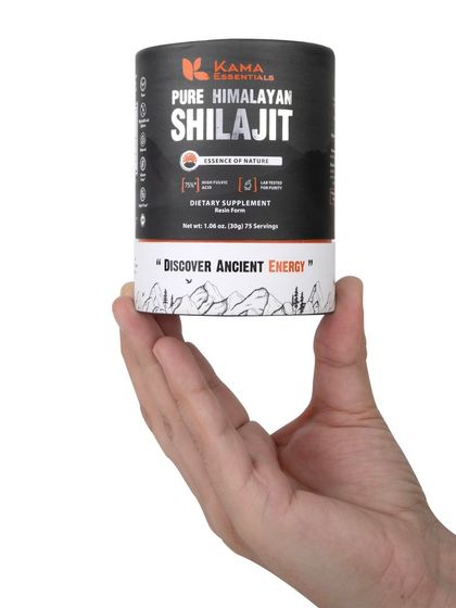 A hand holding the Shilajit packaging, giving a sense of scale and a human touch.
