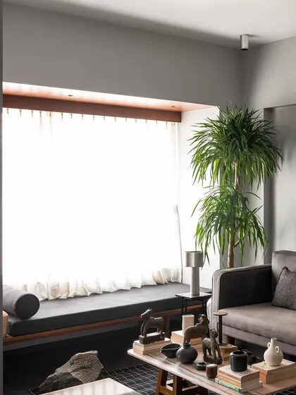 A view of the living room highlighting the window seat I designed. It provides a long, comfortable perch to enjoy the bright light from the large window, with the main seating area arranged for conversation.