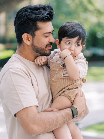 A father holding his son, who is looking thoughtfully at the camera. A beautiful, soulful portrait.