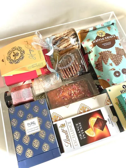 A different angle of the exquisite acrylic trunk hamper, showcasing the variety of high-end snacks and home fragrance items packed inside.