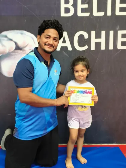 A very young gymnast is happy to receive her first certificate from her coach.