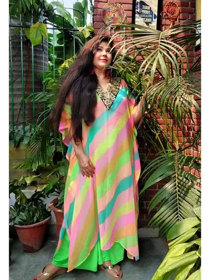 A full-length view of the vibrant rainbow kaftan. This free-flowing silhouette is comfortable for all body types and is made from a lightweight fabric perfect for festive occasions or a beach vacation.