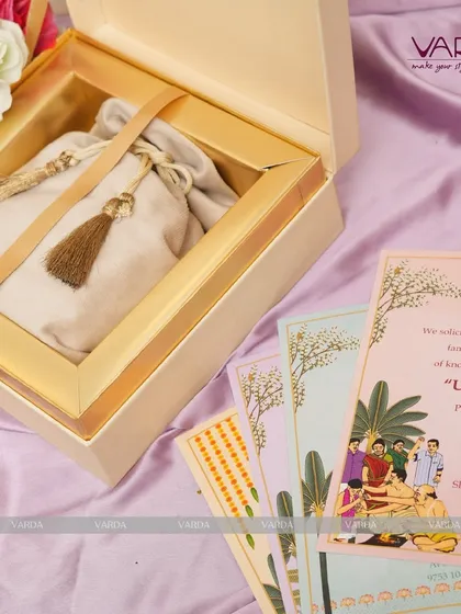 This invitation suite is designed for an Upanayanam ceremony, featuring a beautifully illustrated card depicting the sacred ritual. The accompanying gift box holds a traditional potli bag, blending modern presentation with cultural significance.