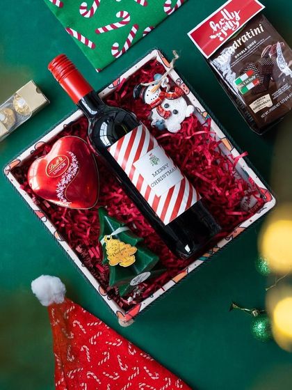 An overhead shot of the 'Jolly Feast' hamper, showing the careful arrangement of wine, chocolates, and ornaments.