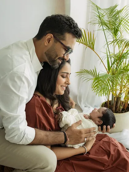 A candid family moment, with parents admiring their newborn baby. The addition of a simple plant adds a touch of nature to this indoor, light-filled session.