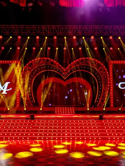 The stage was designed for a spectacle. A heart-shaped LED arch framed the central screen, which featured the couple's custom 'AM' monogram, all set against a backdrop of dynamic stage lighting for the night's performances.