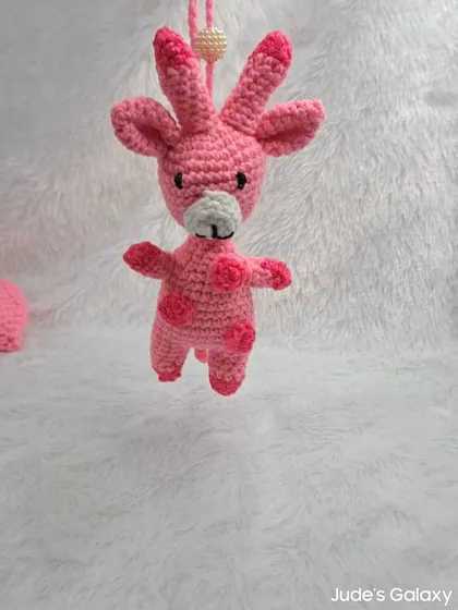 A cute and quirky pink giraffe ornament, complete with spots and ossicones. It's a fun and unique hanging decoration.
