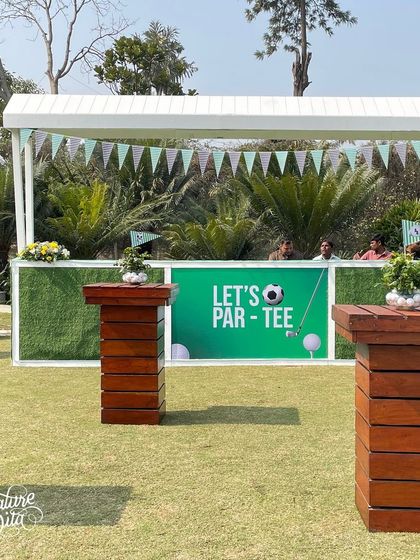 The bar area for the 'Let's Par-Tee' event, with a turf-fronted bar and high-top tables for guests to mingle.