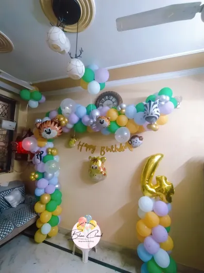 A simple jungle-themed 4th birthday decoration for a home setting, with a balloon arch and animal foils.