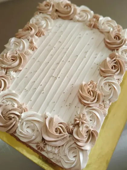 A large rectangular sheet cake decorated with an elegant border of piped rosettes.