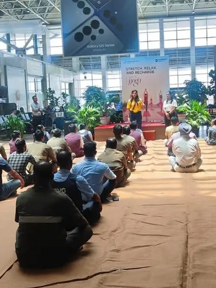 A group of airport ground staff taking a moment for a guided meditation. These short mindfulness breaks are powerful tools for managing the daily pressures of their jobs.